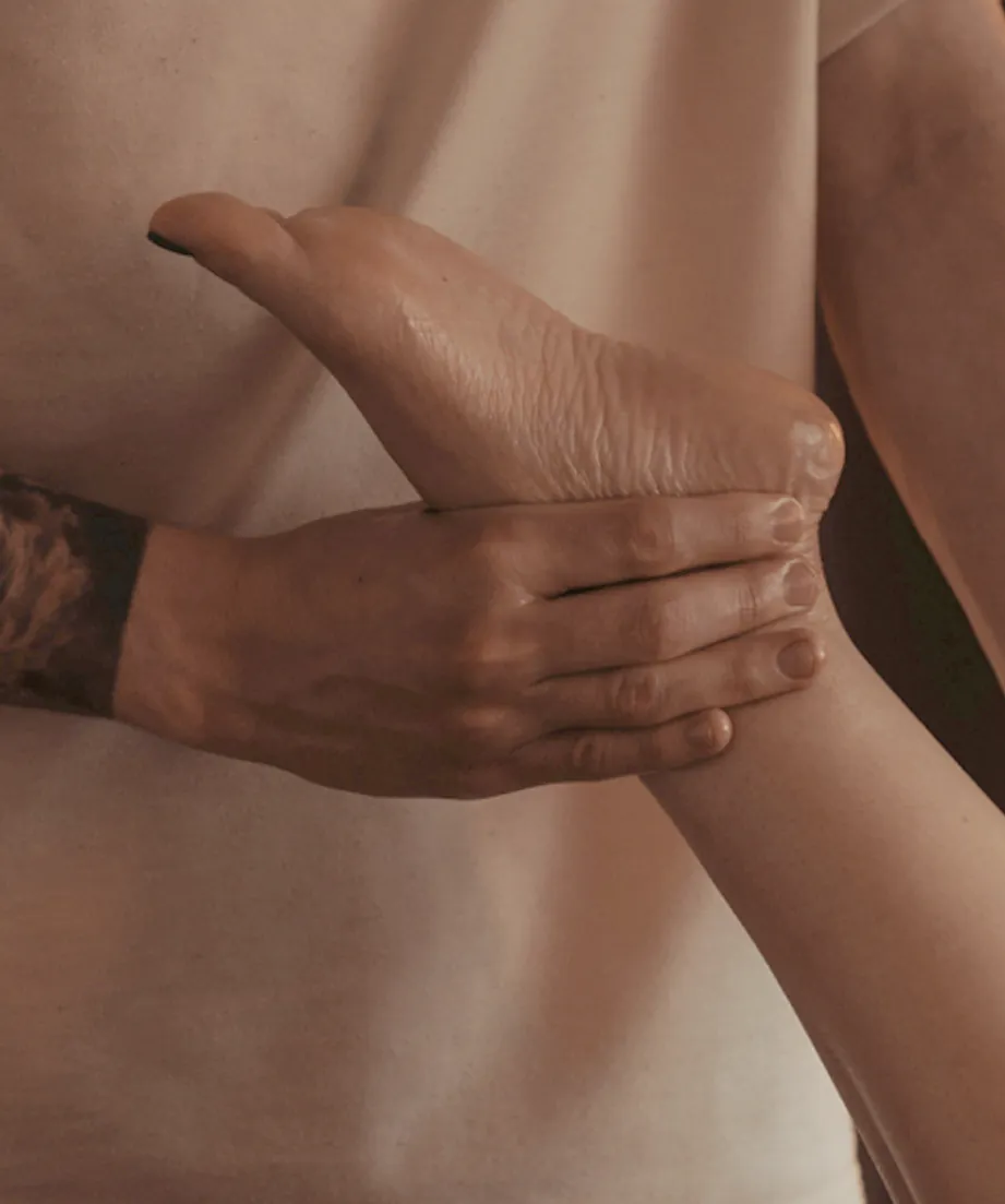 A massage therapist's hand holding the client's foot, lamp light on the skin