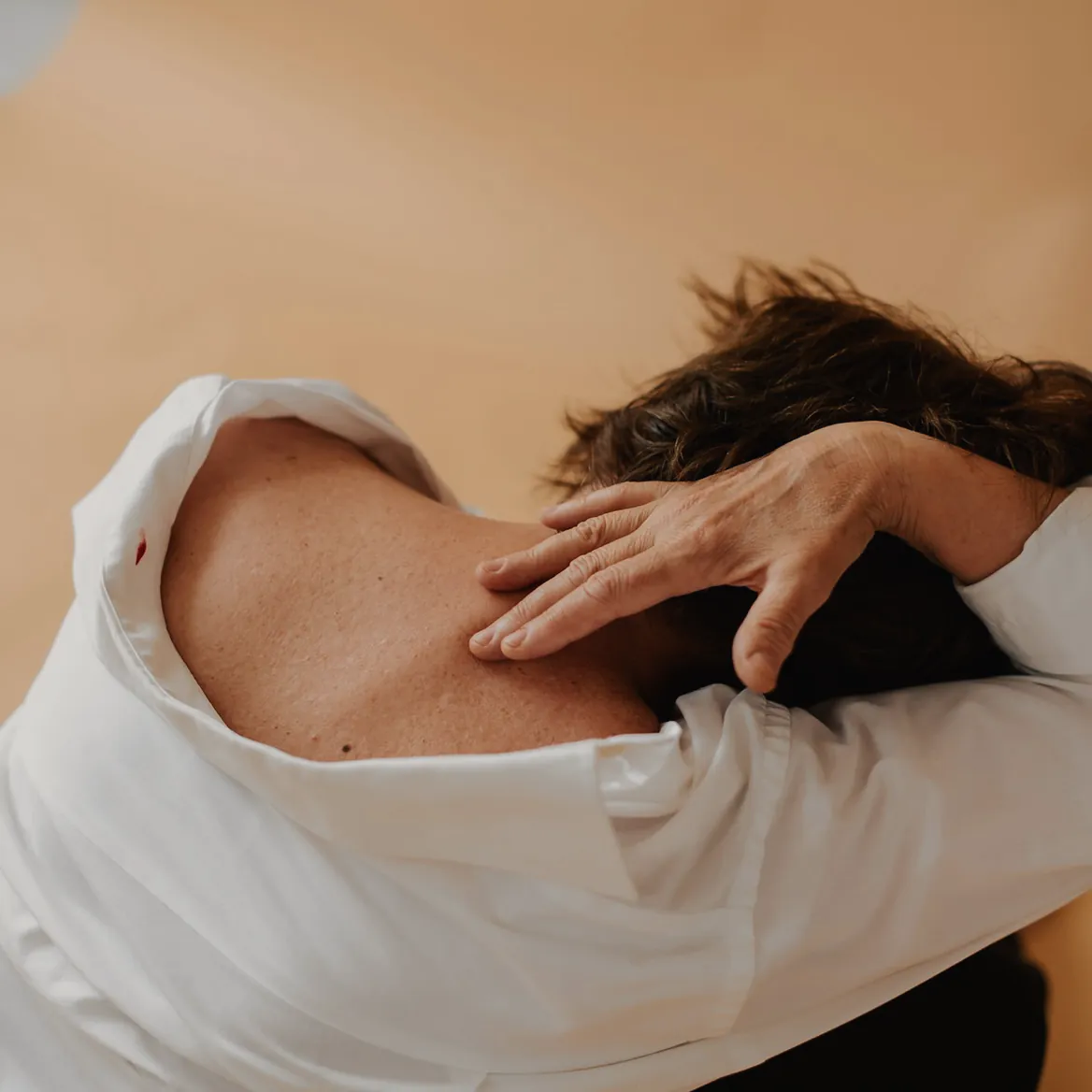 A slow shoulder stretch in a loose white shirt