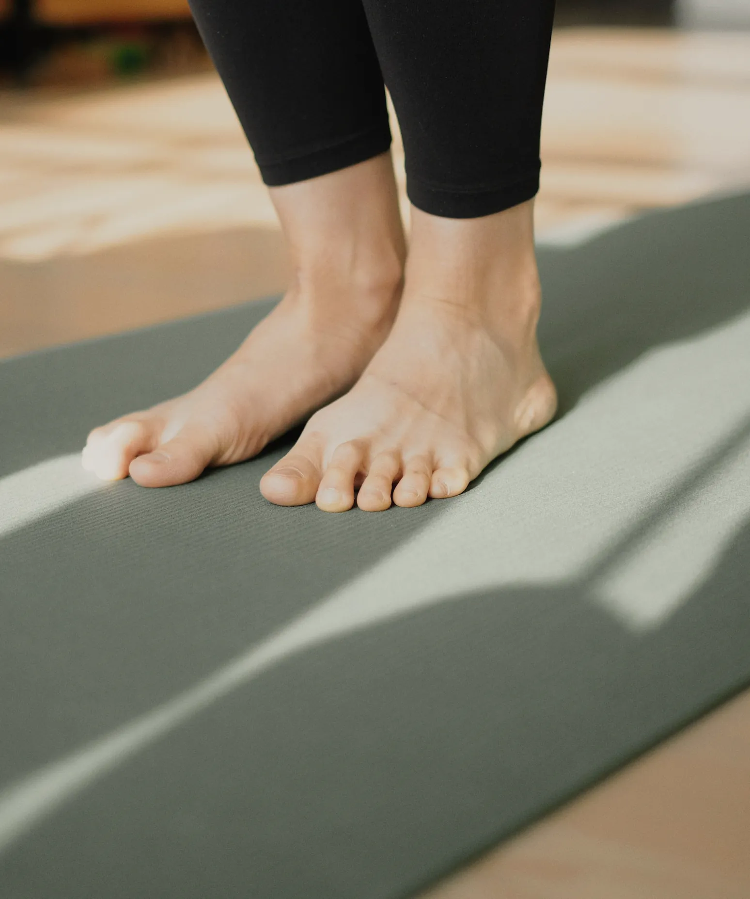 Bare feet standing on a mat in a band of morning sun