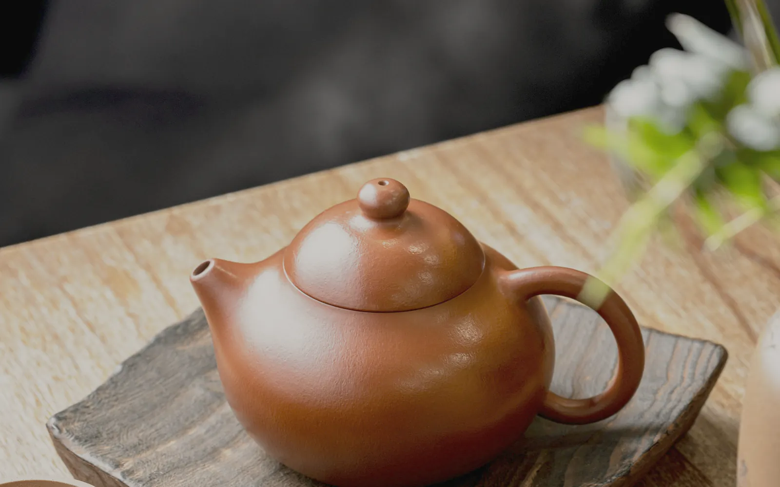 A clay teapot on a timber board in low light