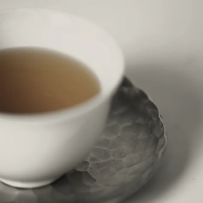 A white cup of pale tea on a grey saucer