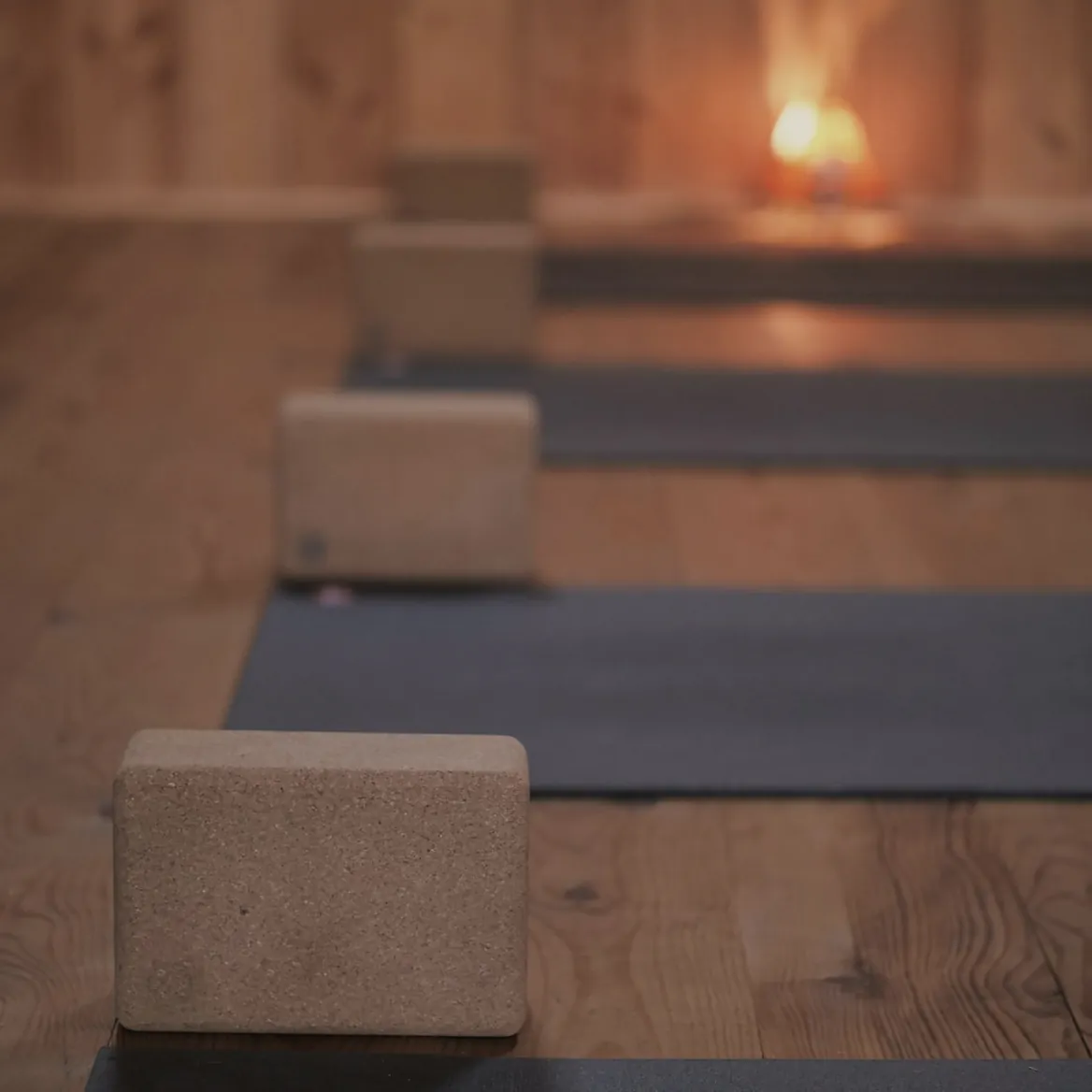 Dark mats in a row on a timber floor, a cork block on each and a small lamp glowing at the end of the room