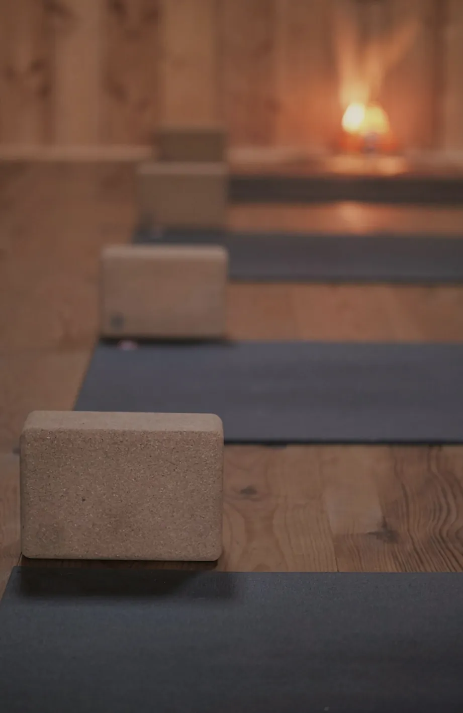 Dark mats in a row on a timber floor, a cork block on each and a small lamp glowing at the end of the room