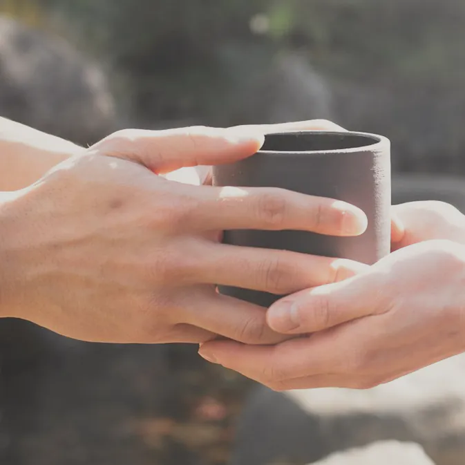 A cup passed from one pair of hands to another